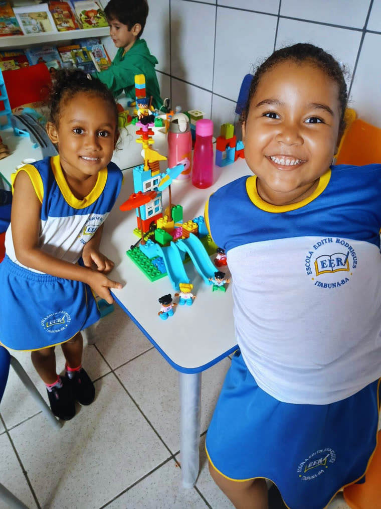 Duas alunas da Educação Infantil sorrindo durante uma atividade em sala