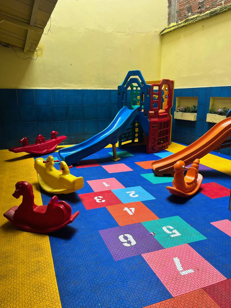 Parque infantil com escorregador, gangorras e piso de amarelinha