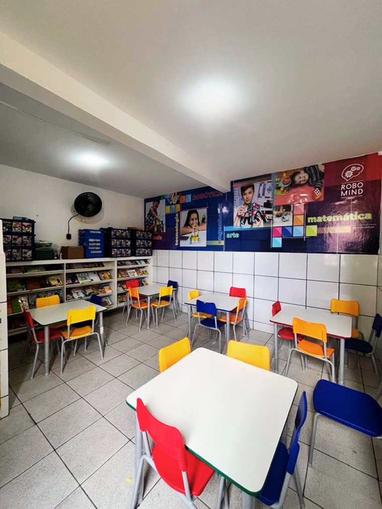 Sala de robótica e leitura, com estantes de livros e mesas de trabalho