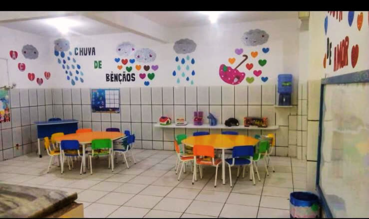 Sala de aula da Educação Infantil com mesas coloridas e mural decorado