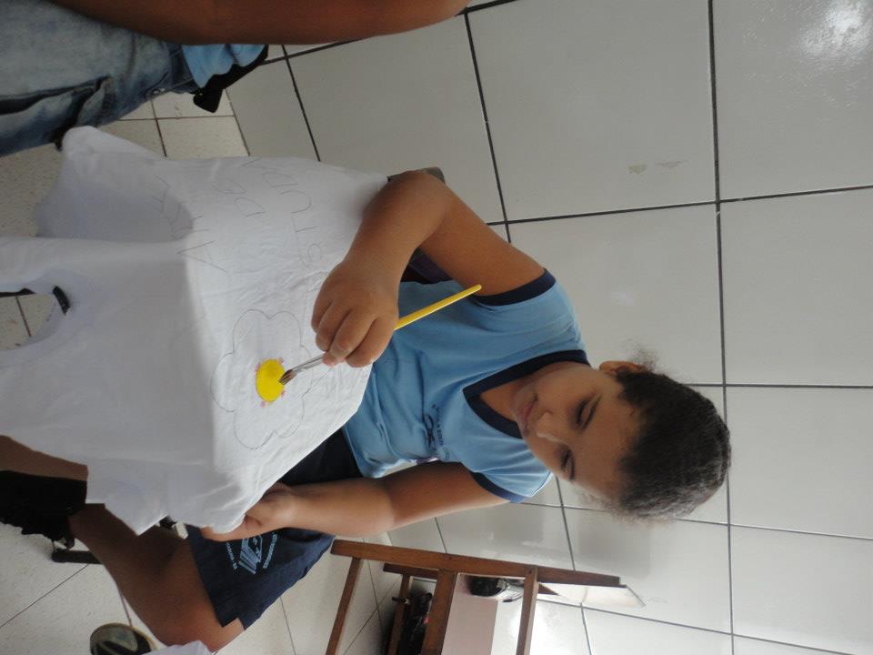 Aluno pintando um trabalho manual apoiado na mesa